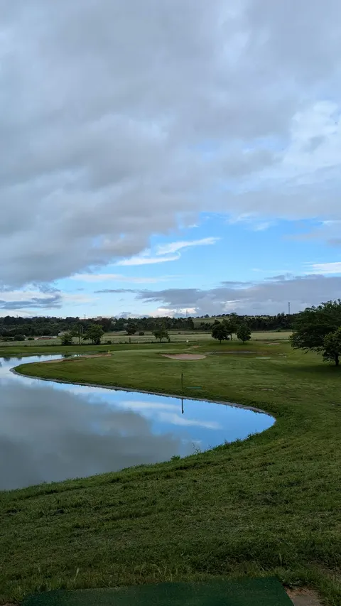 Un llac allargat que serpenteja entre la gespa sota un cel de núvols